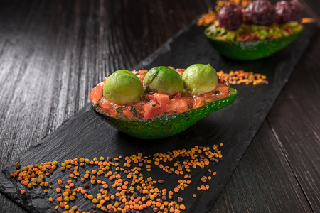 Salmon tartare and avocado salad on a black backgroundの写真素材
