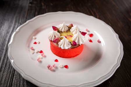 Caramel cheesecake with cream and flowers on the wooden backgroundの写真素材