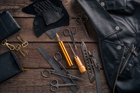 Leather craft or leather working. Leather working tools and cut out pieces of leather on work desk. Still life. Copy space. Top viewの写真素材