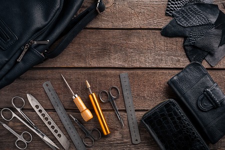 Leather craft or leather working. Leather working tools and cut out pieces of leather on work desk .の写真素材