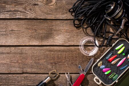 Fishing tackle - fishing spinning, fishing line, hooks and lures on wooden background. Top view. Copy space. Still lifeの写真素材