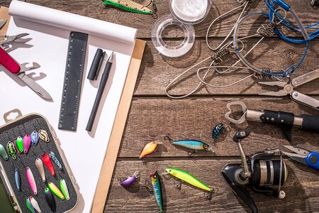 Fishing tackle - fishing spinning, fishing line, hooks and lures on wooden background. Top view. Copy space. Still life Flat layの写真素材