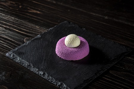 Purple brownie with ice cream. Sweet dessert with ice. The original presentation of the dish from the chef. On a dark wooden background.の写真素材