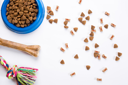 dry pet food in bowl and toys for dogs on white background top viewの写真素材