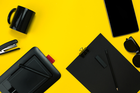Black objects from the office on a yellow background. Work and creativity. Top view.の写真素材