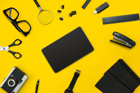 Black objects from the office on a yellow background. Work and creativity. Social media concept hero header image. Top view. Still life. Copy spaceの写真素材