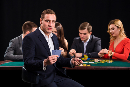 Poker players in casino with cards and chips on black backgroundの写真素材