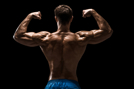 Strong Athletic Man Fitness Model posing back muscles, triceps over black backgroundの写真素材