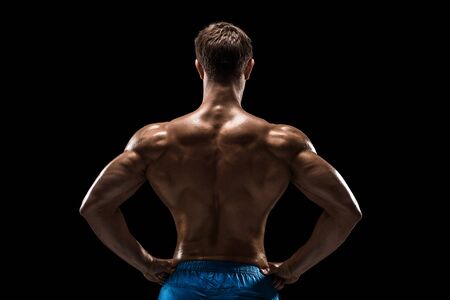 Strong Athletic Man Fitness Model posing back muscles, triceps over black backgroundの写真素材