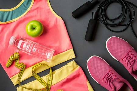 Athletes set with female clothing, sneakers and bottle of water on gray backgroundの写真素材