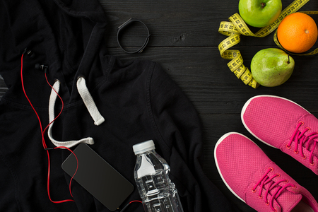 Athletes set with female clothing, sneakers and bottle of water on dark backgroundの写真素材