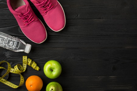 Athletes set with female clothing, sneakers and bottle of water on dark backgroundの写真素材