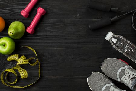 Athletes set with female clothing, sneakers and bottle of water on dark backgroundの写真素材