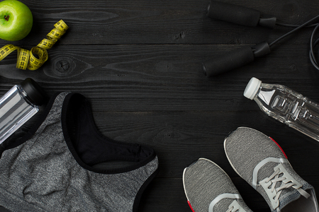 Athletes set with female clothing, sneakers and bottle of water on dark backgroundの写真素材