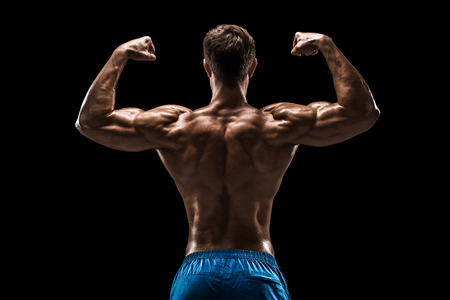 Strong Athletic Man Fitness Model posing back muscles, triceps over black backgroundの写真素材