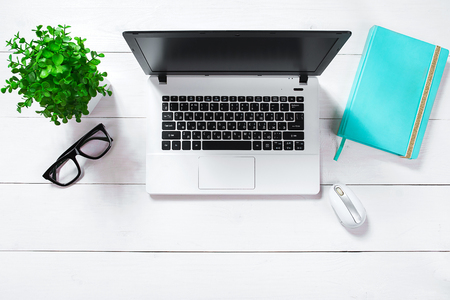 Workspace with laptop, green flower in a pot, mint diary on white background.の写真素材