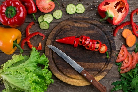 Cut pepper on a wooden board and vegetables on a table