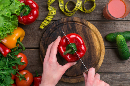 Female hands cutting pepper at table, top viewの写真素材