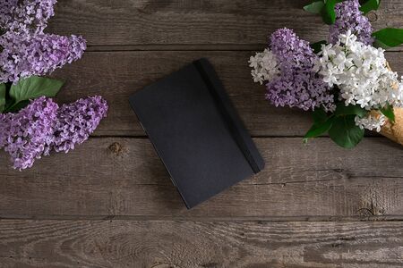 Lilac blossom on rustic wooden background with notebook for greeting message. Top viewの写真素材