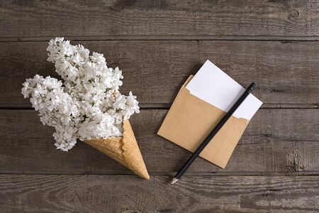 Lilac blossom on rustic wooden background with empty space for greeting message. Small envelope. Top...