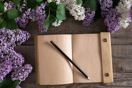 Lilac blossom on rustic wooden background with notebook for greeting message. Top viewの写真素材