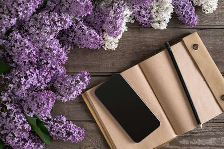 Lilac blossom on rustic wooden background with notebook for greeting message. Top view. Mother's Day. Spring background concept.の写真素材