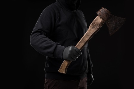 A man in gloves holds an ax in his hands against a black background. Criminalの写真素材