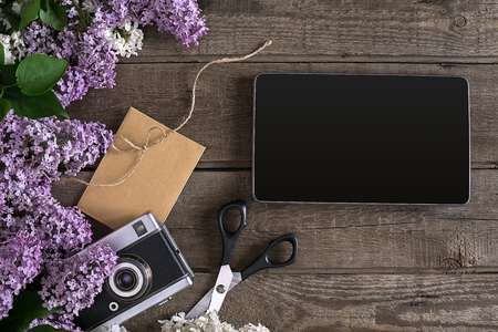 Lilac blossom on rustic wooden background, tablet with empty space for greeting message. Scissors, thread reel, small envelope. Top viewの写真素材