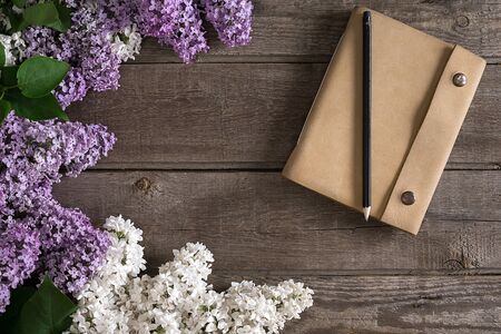 Lilac blossom on rustic wooden background with notebook for greeting message. Top viewの写真素材