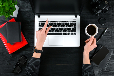 Business and technology topic: the hand of woman in a black shirt showing gesture against background laptop at the desk.の写真素材