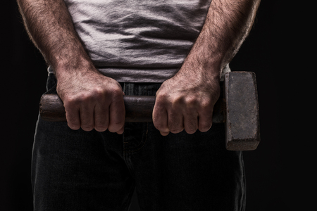 Male offender with a big hammer. On black background at the studioの写真素材