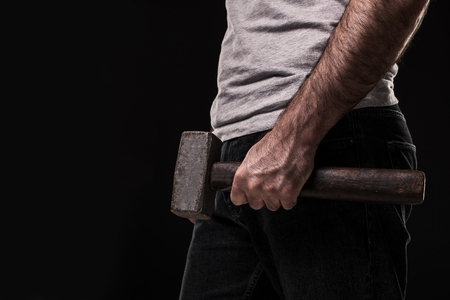 Male offender with a big hammer. On black background at the studioの写真素材