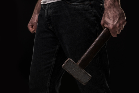 Male offender with a big hammer. On black background at the studioの写真素材