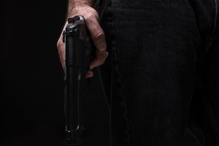 Killer with gun on black background at the studioの写真素材