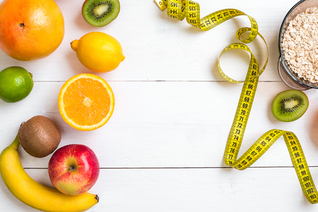 Fitness concept with fruit, bowl of oatmeal and centimeter. Top view background concept.の写真素材