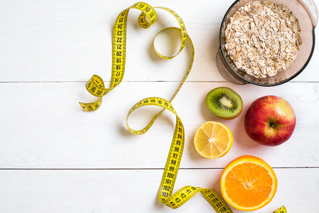 Fitness concept with fruit, bowl of oatmeal and centimeter. Top view background concept.の写真素材