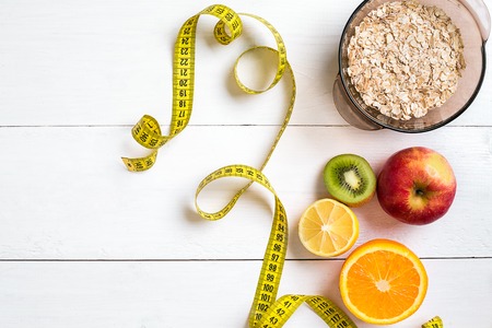Fitness concept with fruit, bowl of oatmeal and centimeter. Top view background concept.の写真素材