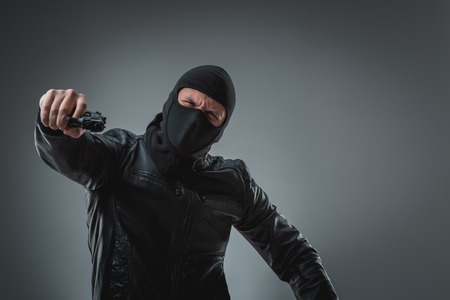 Masked robber with gun, looking into the camera.の写真素材