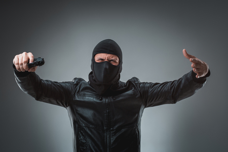 Masked robber with gun, looking into the camera.の写真素材