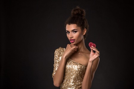 Woman winning - Young woman in a classy gold dress holding two red chips, a poker of aces card combination.の写真素材