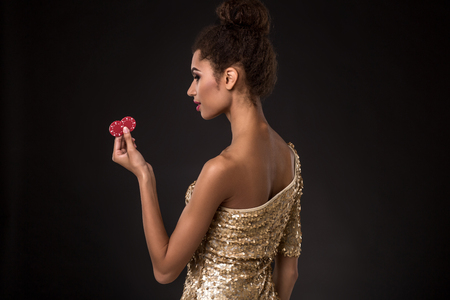 Woman winning - Young woman in a classy gold dress holding two red chips, a poker of aces card combination.の写真素材