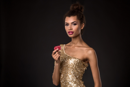 Woman winning - Young woman in a classy gold dress holding two red chips, a poker of aces card combination.の写真素材
