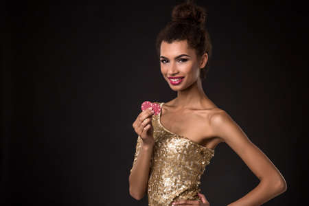 Woman winning - Young woman in a classy gold dress holding two red chips, a poker of aces card combination.の写真素材