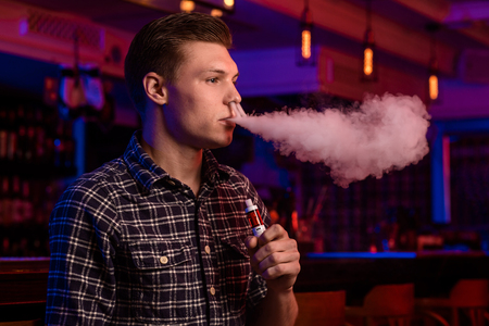 The man smoke an electronic cigarette at the vape shop.の写真素材