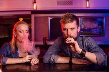A man and woman smoking electronic cigarette in a vape bar.の写真素材