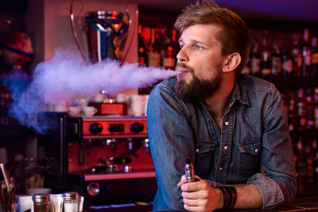 Vape. Vaping man in a cloud of vapor. Photo is taken in a vape bar.の写真素材