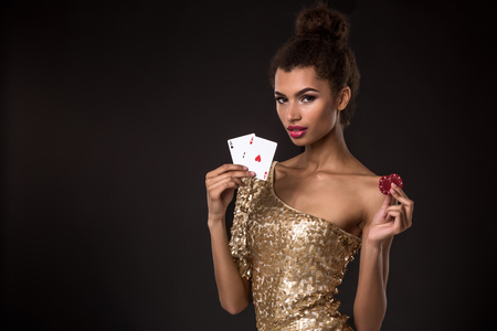 Woman winning - Young woman in a classy gold dress holding two aces and two red chips, a poker of aces card combination.の写真素材