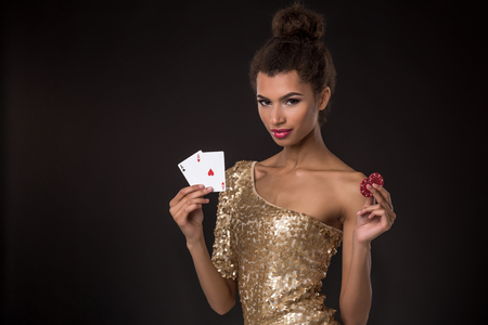 Woman winning - Young woman in a classy gold dress holding two aces and two red chips, a poker of aces card combination.の写真素材