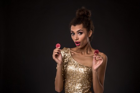 Woman winning - Young woman in a classy gold dress holding two red chips, a poker of aces card combination.の写真素材