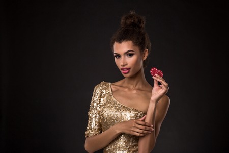 Woman winning - Young woman in a classy gold dress holding two red chips, a poker of aces card combination.の写真素材
